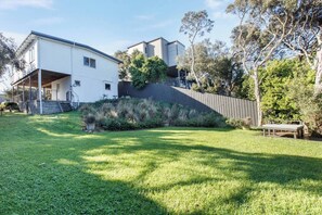 A residential property with a covered patio, a fenced yard, and mature trees. - Bayview Cottage Serene Escape between Beach and Bay (Blairgowrie)