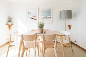 Un coin repas avec une table ronde, quatre chaises, une lampe et deux tableaux encadrés accrochés au mur.
