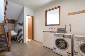 Une buanderie équipée d’un lave-linge, d’un sèche-linge et d’un petit évier.