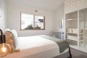 A bedroom with a bed, a bedside table, a wardrobe, a window, and a mirror. - Bayview Cottage Serene Escape between Beach and Bay (Blairgowrie)