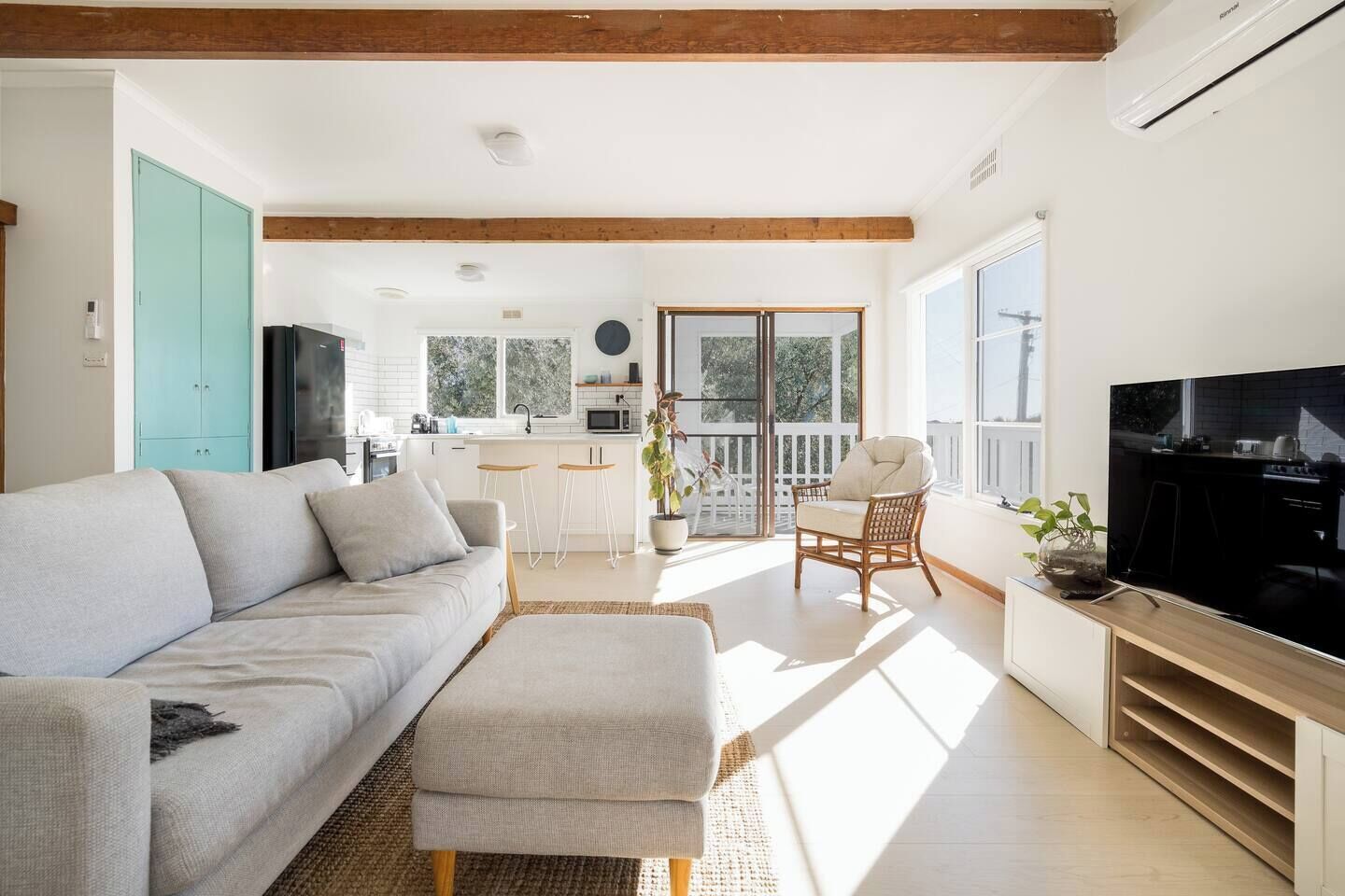 Uma sala de estar moderna com um sofá, um banquinho e uma televisão.