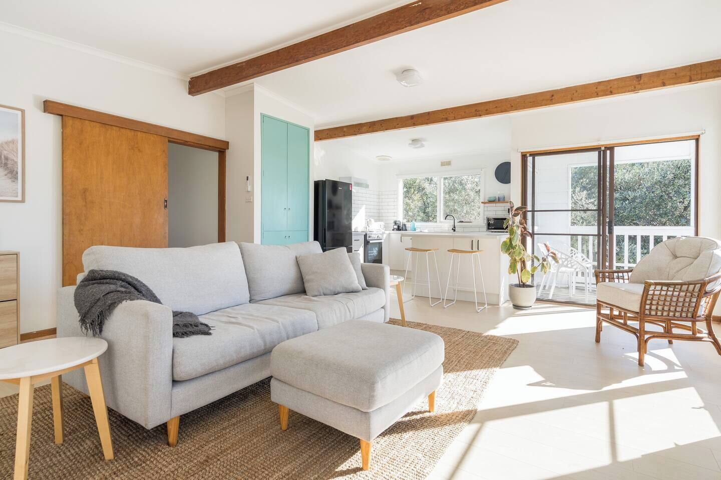 A modern living room with a sofa, a small table, and a wicker chair.