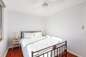 Ein Schlafzimmer mit einem Bett, Nachttischen, einem Deckenventilator und einem Fenster.