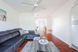 Ein modernes Wohnzimmer mit Ledersofa, Couchtisch und Deckenventilator.