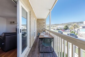 A balcony with a dining table set for four, a sofa, and a view of a residential area with cars and buildings. - Sea Quinn Escape Steps to Dromana Beach and Dining (Dromana)
