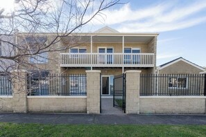 Ein zweistöckiges Wohngebäude mit einem Balkon im oberen Geschoss, einem verschlossenen Eingang und einer Ziegel Fassade.