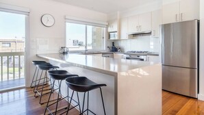 Una cocina moderna con una isla grande, electrodomésticos de acero inoxidable y vistas al exterior.