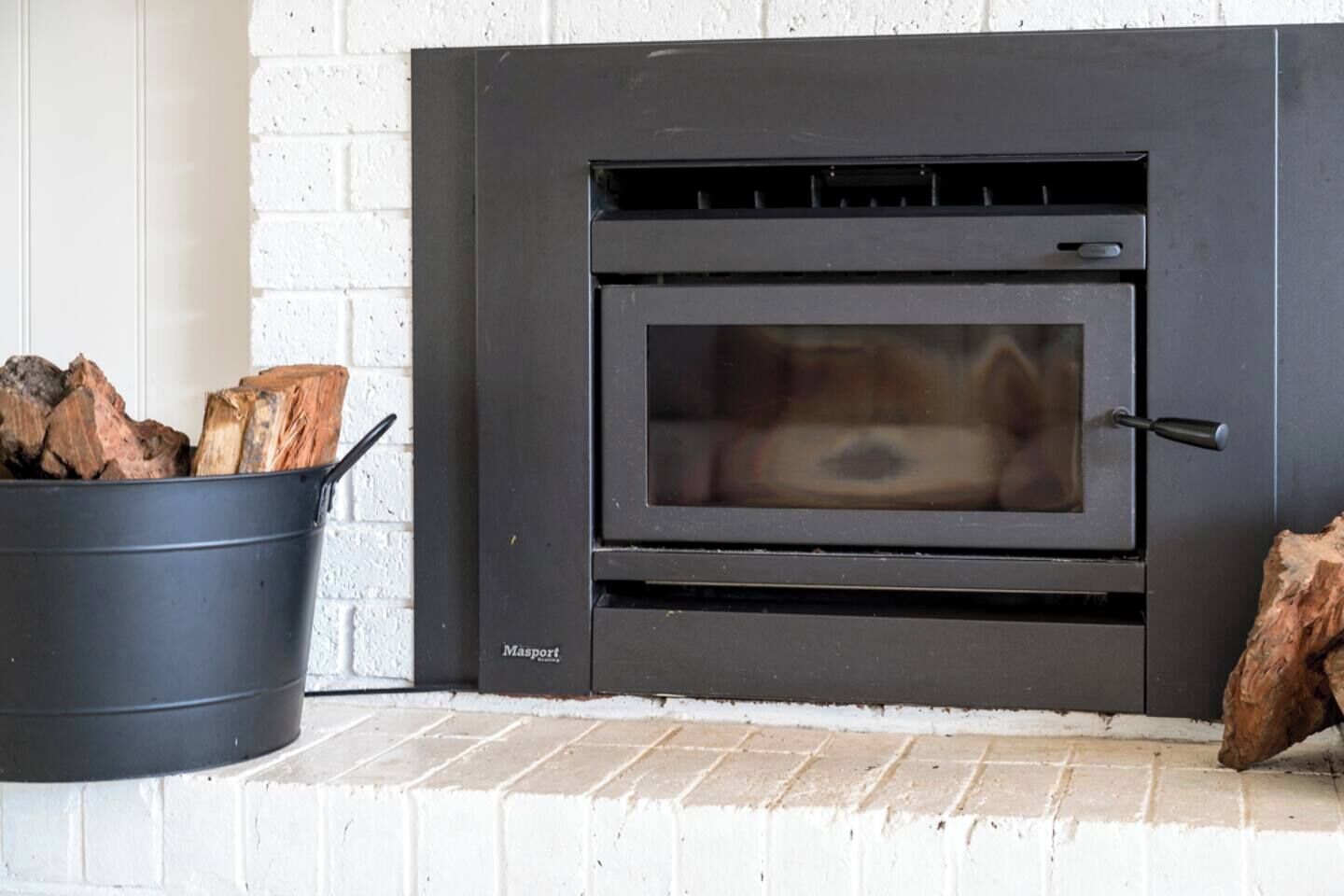 Ein moderner Kamin mit schwarzer Außenseite, einer Glasscheibe und einem sichtbaren Feuerraum.