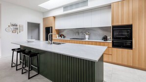 Una cocina moderna con una isla central, electrodomésticos de acero inoxidable y un techo alto con tragaluces.