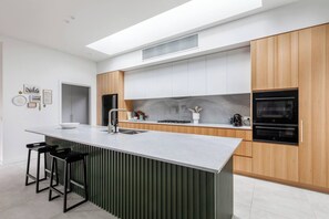 Eine moderne Küche mit Kochinsel, Edelstahlgeräten und einer hohen Decke mit Dachfenster.