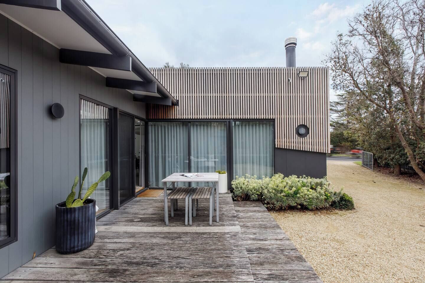 Une maison moderne avec un patio, une table et une plante en pot.
