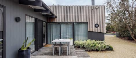 A modern house with a patio, a table, and a potted plant.