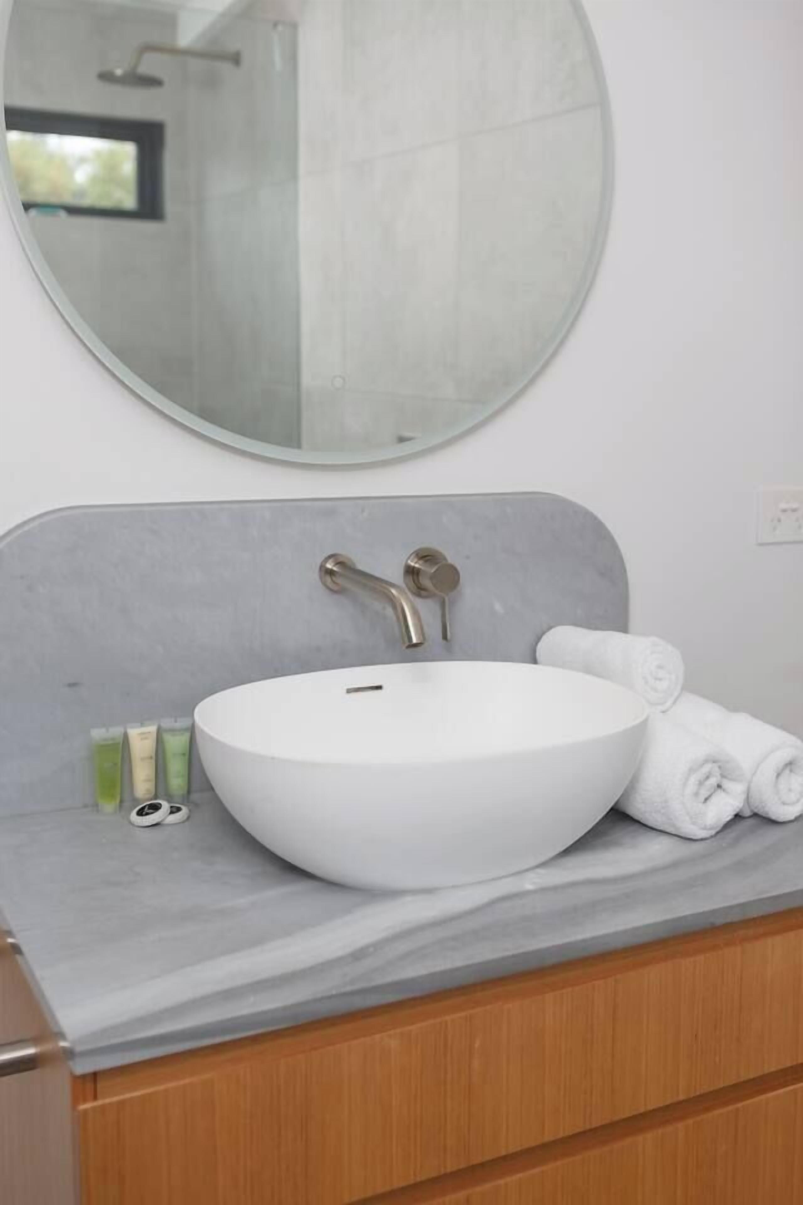 A bathroom with a round mirror, a white sink, and a towel on the counter.