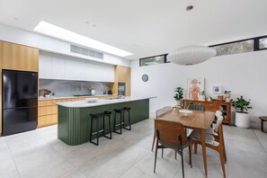 Une cuisine moderne dotée d’un îlot central, de tabourets de bar et d’un coin repas avec une table et des chaises en bois.