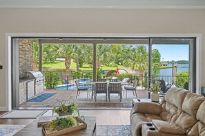 Un grand balcon avec une piscine, du mobilier d’extérieur et une vue sur un lac.