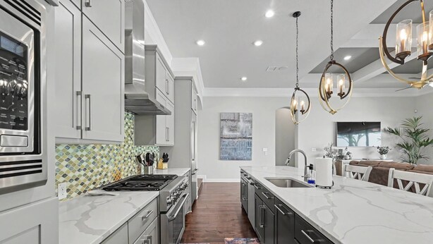 A modern kitchen with stainless steel appliances, a marble countertop, and pendant lighting. - 5BR Lakefront Retreat | Pool + Hot Tub | Private Dock | Pet Friendly | Swim, Fish & Boat (Montgomery)