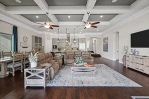 A spacious living room with a large sectional sofa, a coffee table, and a dining area with wooden chairs. - 5BR Lakefront Retreat | Pool + Hot Tub | Private Dock | Pet Friendly | Swim, Fish & Boat (Montgomery)
