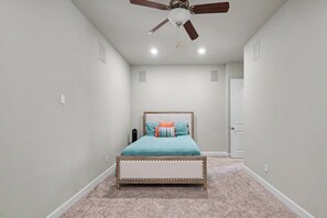 Ein Schlafzimmer mit Bett, Deckenventilator und Tür.