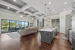 Une cuisine spacieuse dotée d’un grand îlot central, d’appareils électroménagers modernes et offrant une vue sur un espace extérieur verdoyant.