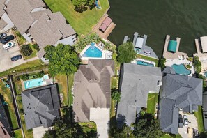 Vista aèria d'una zona residencial amb cases, una piscina i un moll al costat d'una massa d'aigua.