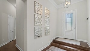 A hallway with a white door, a staircase, and decorative wall panels. - 5BR Lakefront Retreat | Pool + Hot Tub | Private Dock | Pet Friendly | Swim, Fish & Boat (Montgomery)