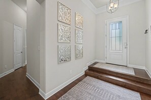 A hallway with a white door, a staircase, and decorative wall panels. - 5BR Lakefront Retreat | Pool + Hot Tub | Private Dock | Pet Friendly | Swim, Fish & Boat (Montgomery)