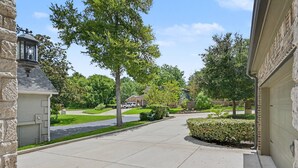 A residential driveway with a stone wall on the left, a garage on the right, and a well-maintained lawn with trees. - 5BR Lakefront Retreat | Pool + Hot Tub | Private Dock | Pet Friendly | Swim, Fish & Boat (Montgomery)