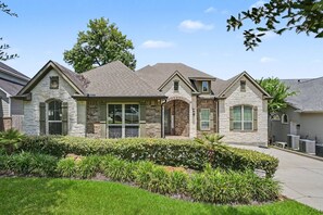A two-story house with a stone facade, a front porch, and a well-maintained lawn. - 5BR Lakefront Retreat | Pool + Hot Tub | Private Dock | Pet Friendly | Swim, Fish & Boat (Montgomery)
