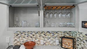 A kitchen with a white backsplash, a wooden bowl, and a framed picture of corks. - 5BR Lakefront Retreat | Pool + Hot Tub | Private Dock | Pet Friendly | Swim, Fish & Boat (Montgomery)
