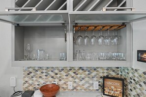 A kitchen with a white backsplash, a wooden bowl, and a framed picture of corks. - 5BR Lakefront Retreat | Pool + Hot Tub | Private Dock | Pet Friendly | Swim, Fish & Boat (Montgomery)