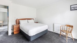 Een slaapkamer met een bed, nachtkastje, stoel en radiator.
