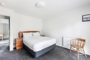 Ein Schlafzimmer mit einem Bett, einem Nachttisch, einem Sessel und einer Heizung.