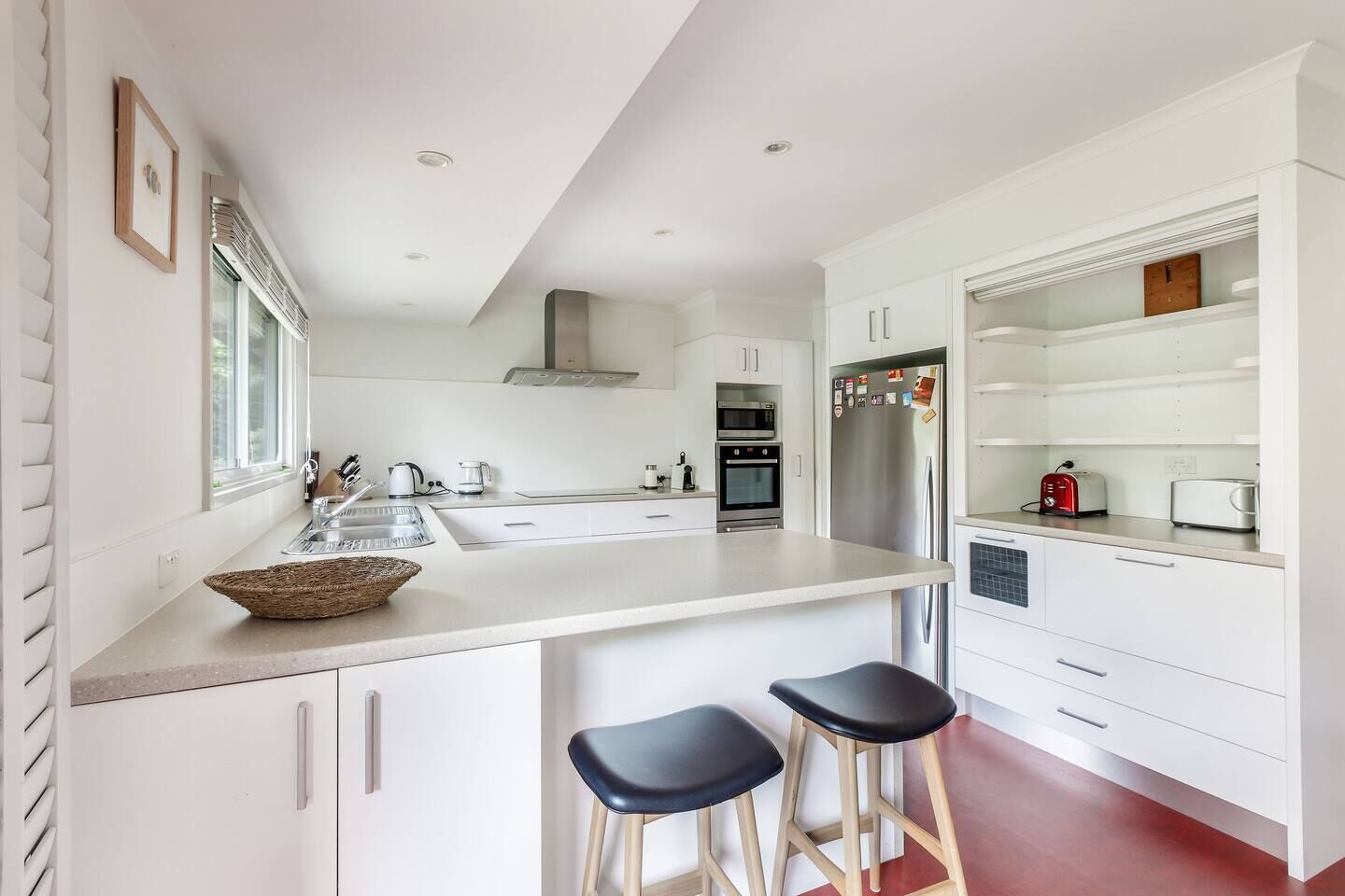 A modern kitchen with a large island, stainless steel appliances, and a red floor.