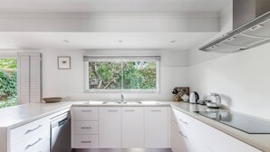 Een moderne keuken met witte kasten, een dubbele spoelbak en een raam met uitzicht op groen.