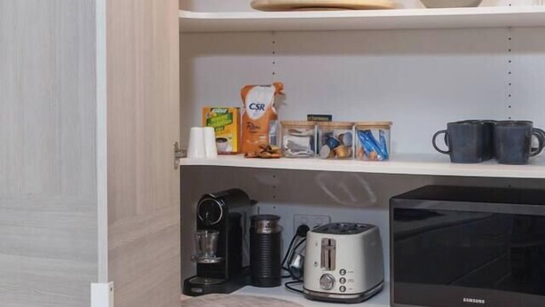 Eine Küche mit Mikrowelle, Toaster, Kaffeemaschine und verschiedenen Küchenutensilien auf der Arbeitsfläche.