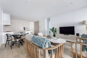 A modern living room with a sofa, coffee table, and TV. - Bayside Calm Walk to Mornington Foreshore and Dining (Mornington)
