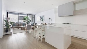 Eine moderne Küche mit Kochinsel, weißen Schränken und einem Essbereich mit Sofa und Stühlen.