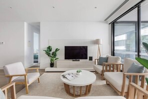 A modern living room with a flat-screen TV, a round coffee table, and a sofa set. - Bayside Calm Walk to Mornington Foreshore and Dining (Mornington)