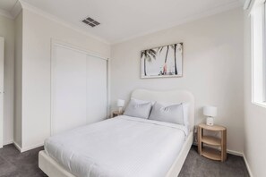Ein Schlafzimmer mit einem Bett, Nachttischen, einem Gemälde und einem Fenster.