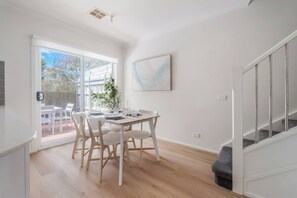 Ein stilvoller Essbereich mit einem Tisch für vier Personen, einer Zimmerpflanze und einer Treppe rechts.