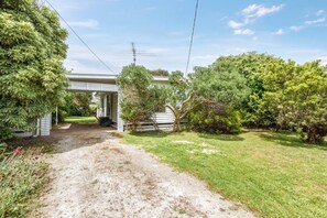 A residential property with a covered driveway, a lawn, and mature trees. - Bayside Cottage Leafy Stay near Rye Beach and Dining (Rye)