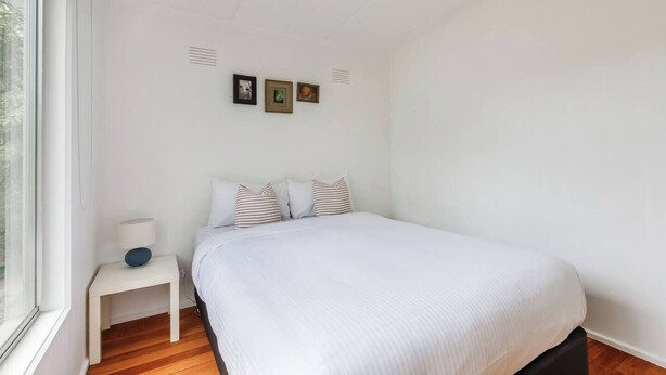 Une chambre à coucher avec un lit, une table de chevet et une fenêtre.