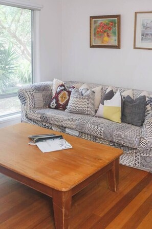 A living room with a patterned sofa, a wooden coffee table, and two framed artworks on the wall. - Bayside Cottage Leafy Stay near Rye Beach and Dining (Rye)