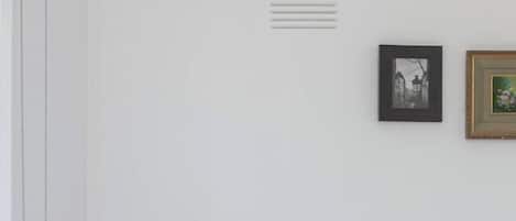 Un dormitorio con una cama, una mesita de noche, una lámpara y dos cuadros en la pared.