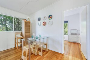 A modern interior with a glass dining table, wooden chairs, and a white wardrobe. - Bayside Cottage Leafy Stay near Rye Beach and Dining (Rye)