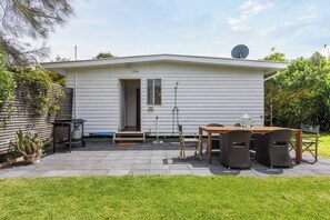 A single-story mobile home with a patio area featuring a table and chairs, a satellite dish, and a small entryway. - Bayside Cottage Leafy Stay near Rye Beach and Dining (Rye)
