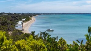 Une vue côtière avec une plage, un voilier et une rangée de bâtiments le long de la côte.