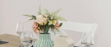 A dining table set with a vase of flowers, a candle, and a decorative object.