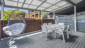 A covered outdoor patio with a hanging chair and a table with chairs. - Foreshore Haven Poolside Comfort near Rye Beach (Rye)