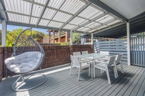Eine überdachte Terrasse im Freien mit einer Hängematte und einem Tisch mit Stühlen.